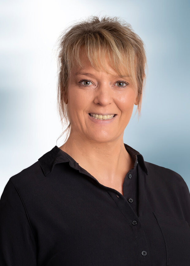Sandra Will, Versand, hat blonde Haare zu einem Pferdeschwanz gebunden mit Pony und trägt eine schwarze Bluse.
