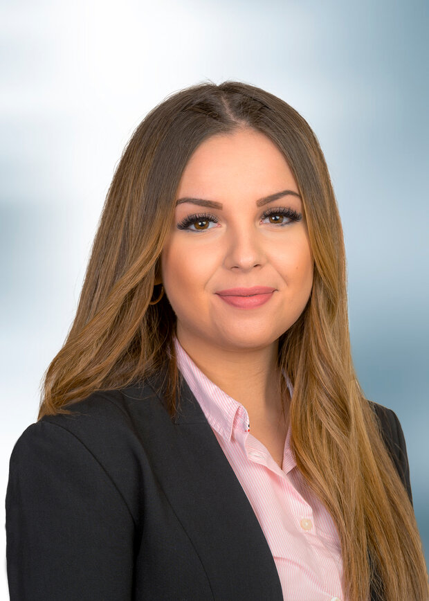 Anna Braun, Vertrieb Außendienst, hat lange braune Haare und trägt eine rosa Bluse mit schwarzem Jacket.