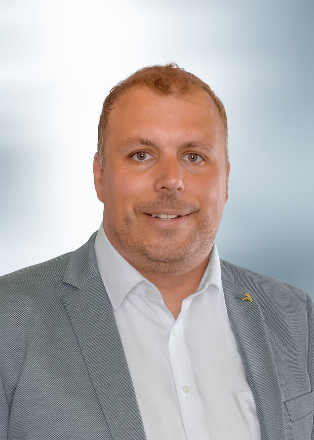 Benedikt Gadzinski, Instandhaltung, hat kurze dunkelblonde Haare und trägt ein weißes Hemd mit blauem Anzug.