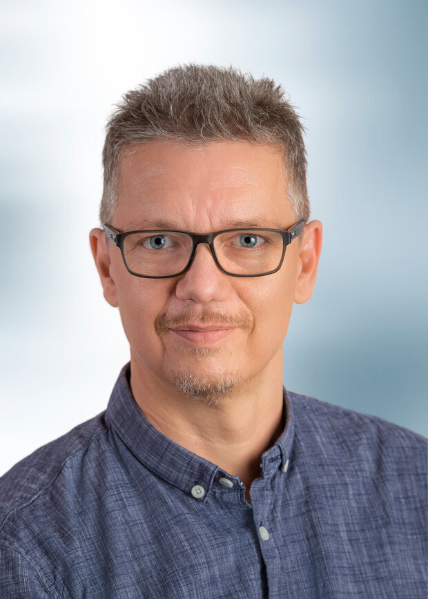 Thomas Grosshardt, Verwaltung, hat kurze graue Haare trägt eine Brille und ein blaues Hemd.