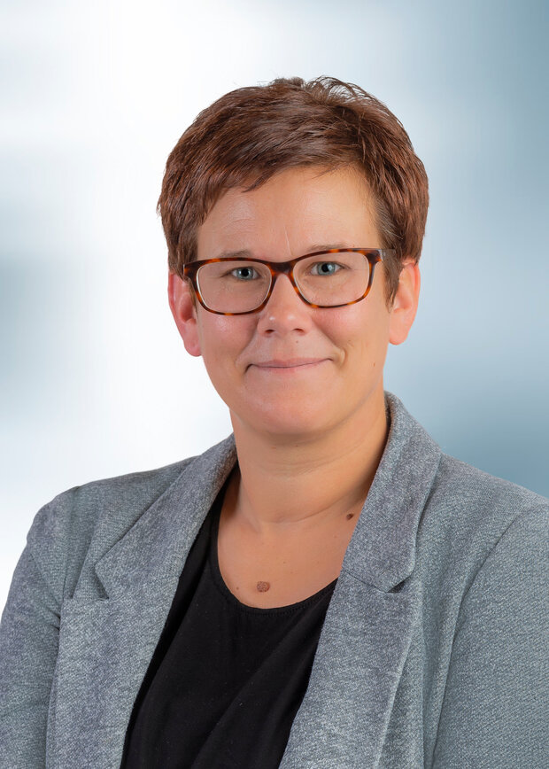 Bianca Krüger, Qualitätssicherung, hat kurze braune Haare, trägt eine Brille und schwarzes T-Shirt mit einem hellgrauen Blazer.