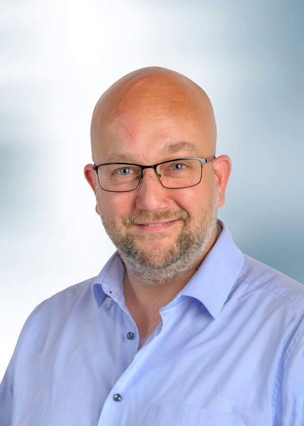 Kay Isbrandt, Instandhaltung, hat eine Glatze, trägt eine Brille und ein hellblaues Hemd. 