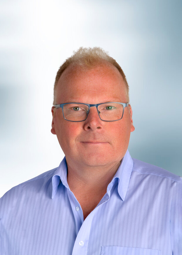 Frank Parensen, Produktion, hat blonde kurze Haare, trägt eine Brille und ein hellblaues Hemd. 