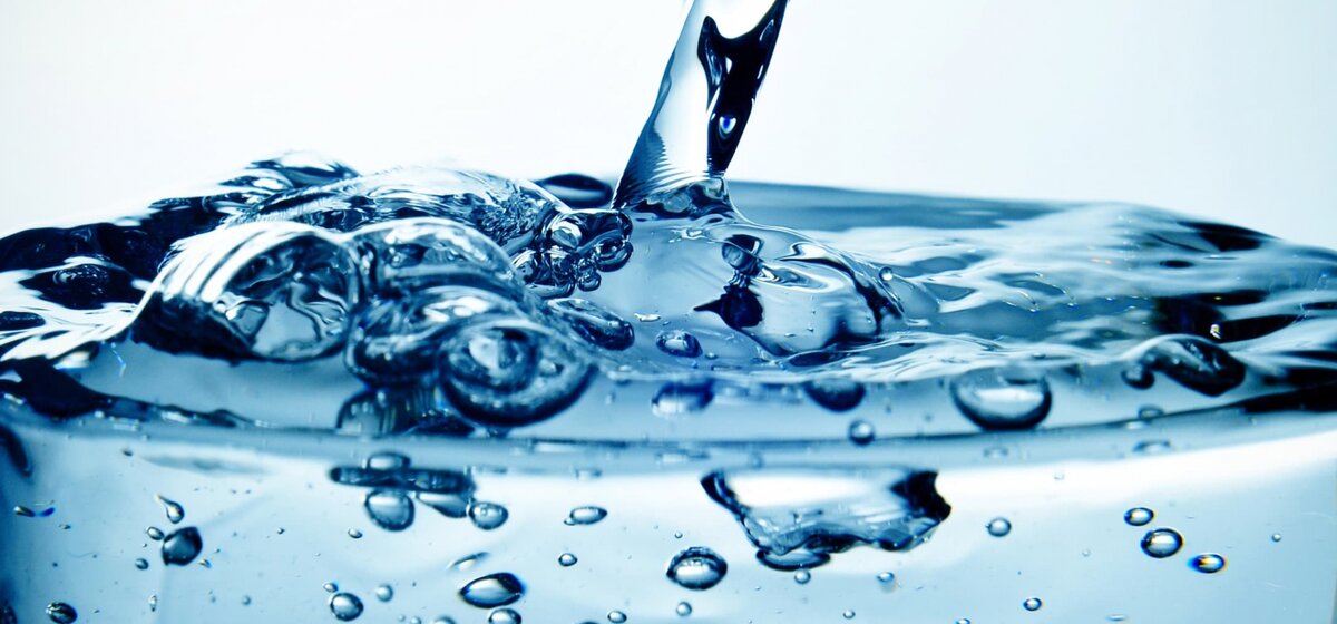 Wasserbewegung in einem Glas mit Luftblasen vor blauem Hintergrund.