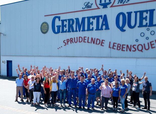 Viele Germete Mitarbeiter stehen vor einem Gebäude.