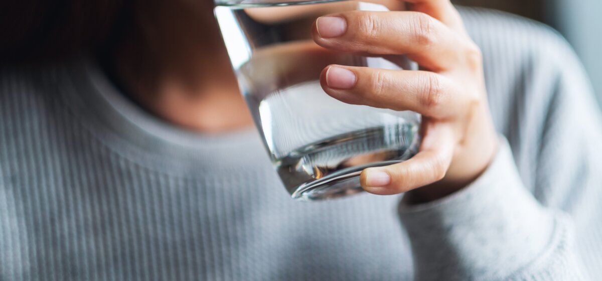 Frau mit Glas in der Hand trinkt Wasser. 