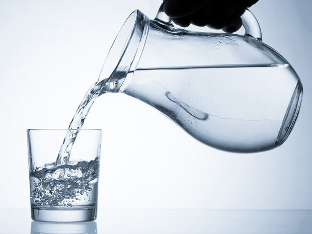 Wasserkrug füllt ein Glas.